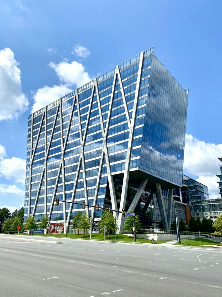 A striking modern office building with a geometric glass facade in an urban setting.
